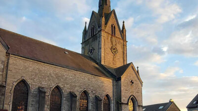 Église Saint-Hubert de Redu avec clocher et vitraux, vue depuis la place du village